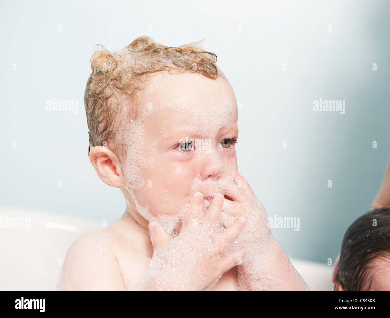 Toddler crying in bubble bath Stock Photo
