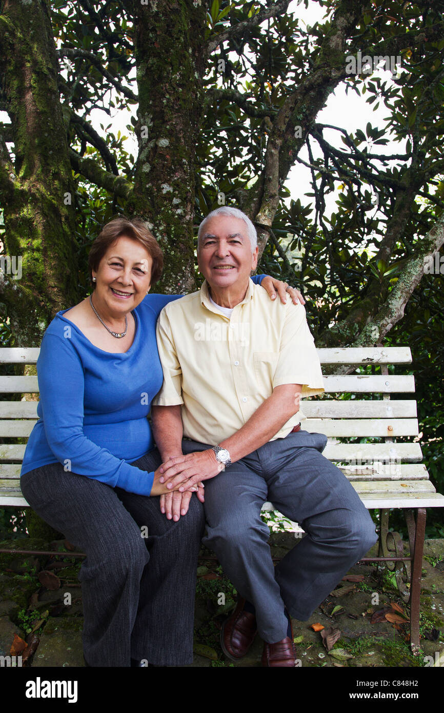Senior Hispanic couple sitting on park bench Stock Photo - Alamy
