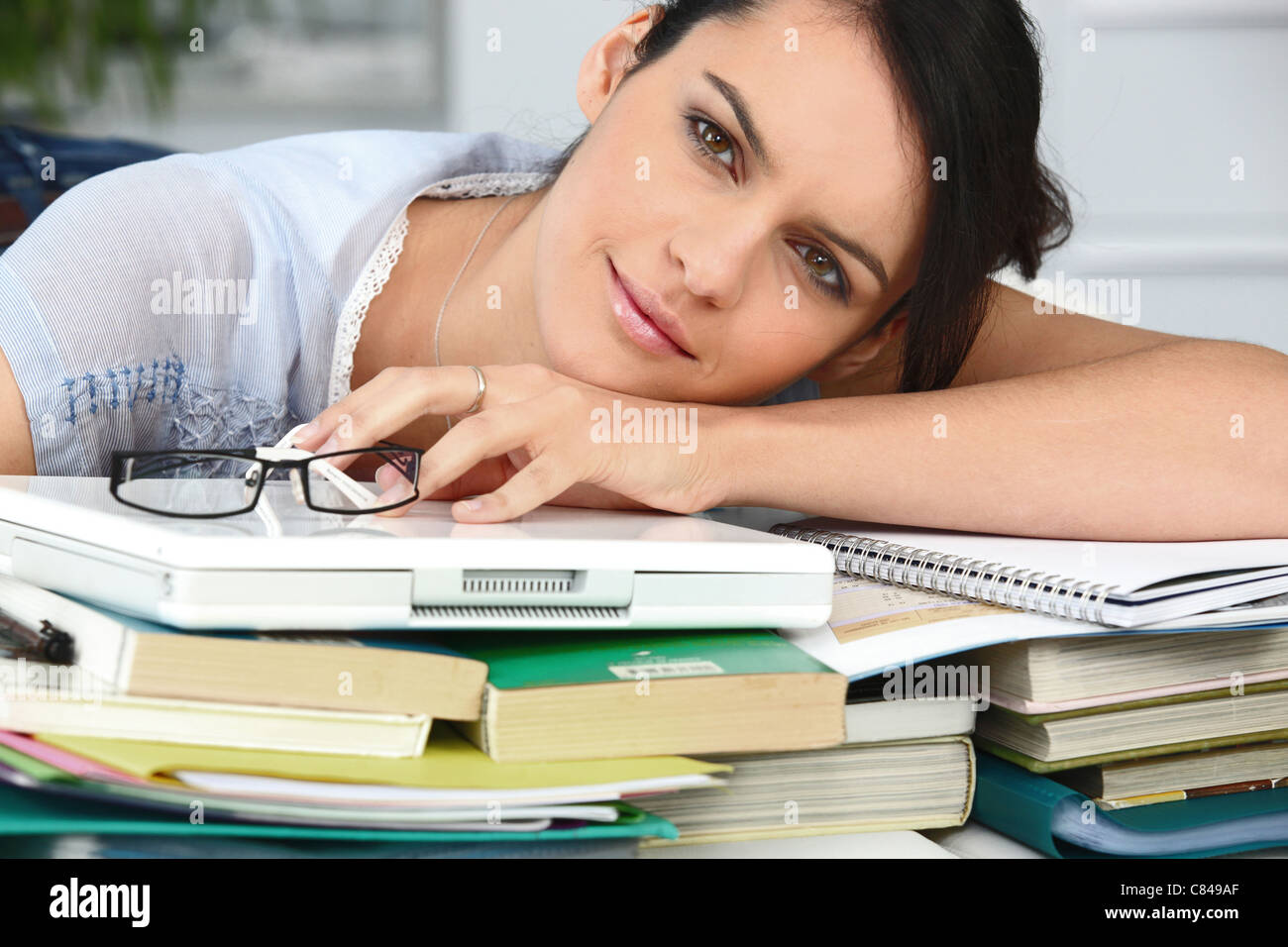 Tired student leaning on a pile of books Stock Photo - Alamy