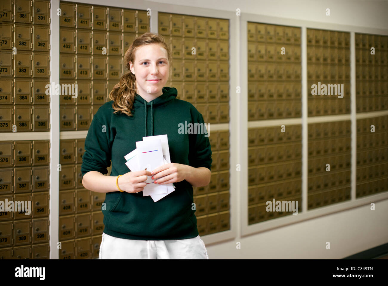 Smiling Caucasian woman holding letters in mailroom Stock Photo
