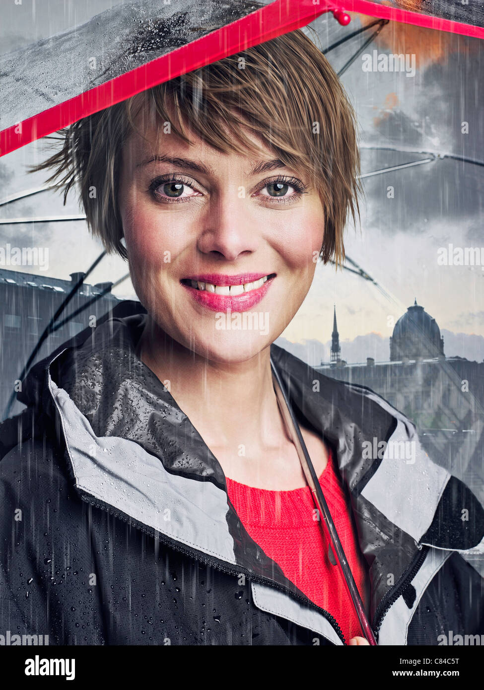 Smiling woman under umbrella in rain Stock Photo