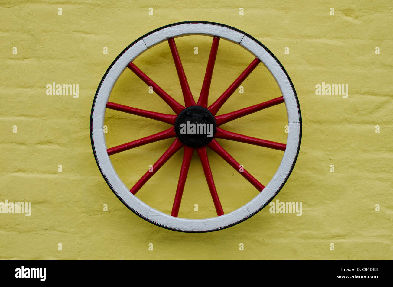 Red wheel on a yellow wall Stock Photo