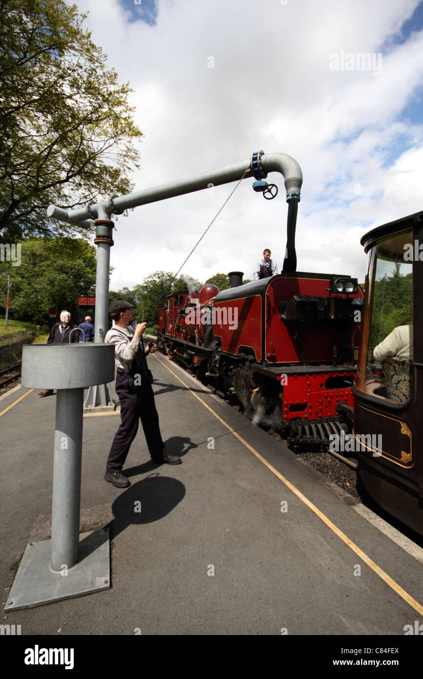 Man pulling water pipe round to fill up a Steam train on the Welsh