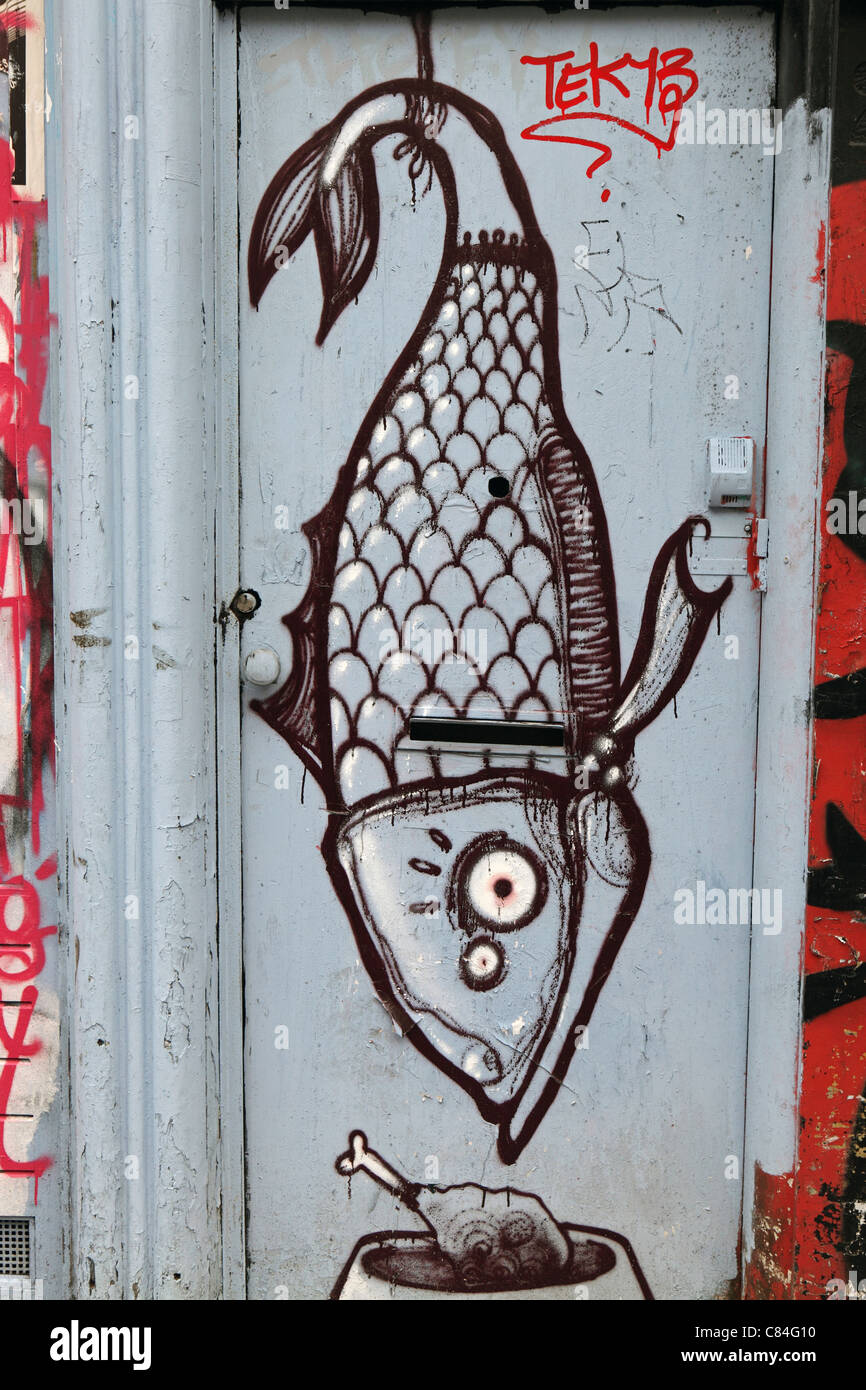 graffiti image of hanging fish on doorway in Amsterdam, vertical image, creative, artistic, surreal, counterculture, vandalism Stock Photo