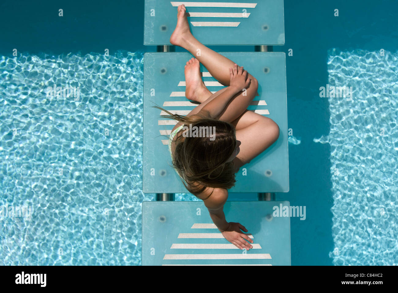 Woman relaxing on swimming pool footbridge Stock Photo