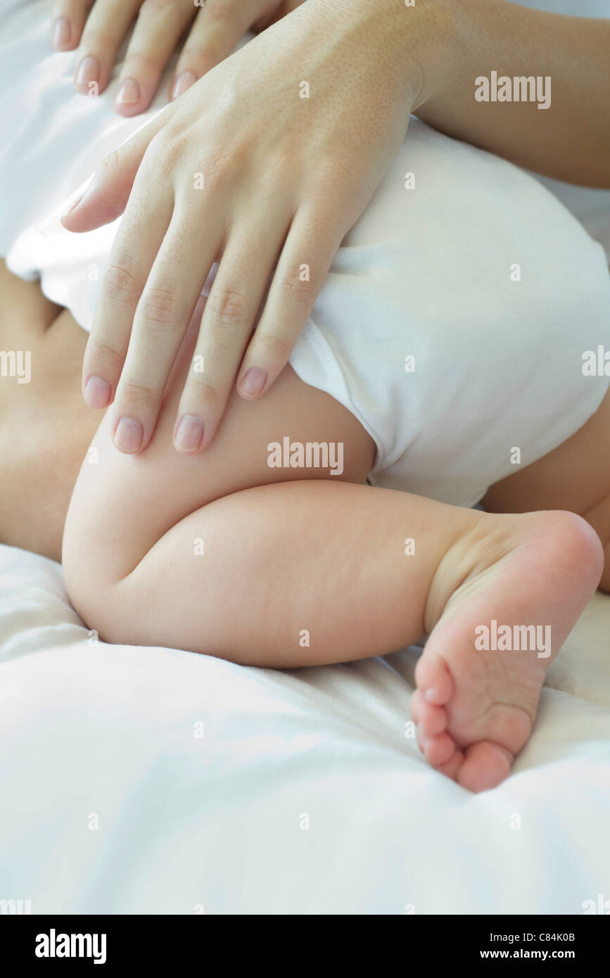 Mother's hand touching baby's leg Stock Photo