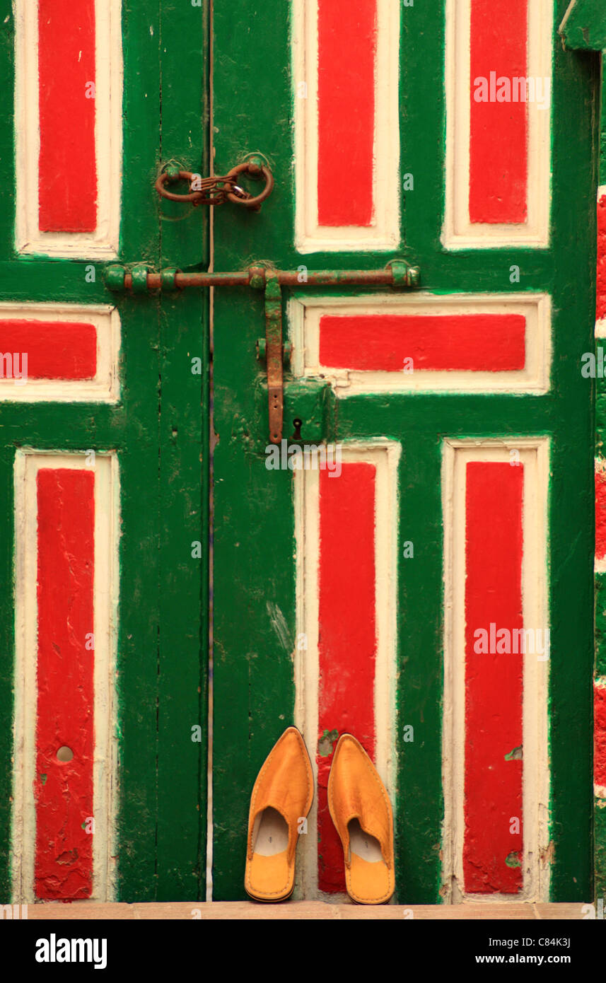 Traditional Moroccan slippers/babouches leaning against decorated typical wooden Moroccan door, medina, Essaouira, Morocco Stock Photo