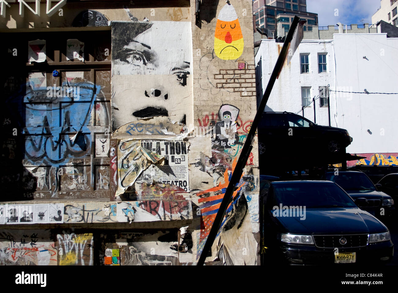graffiti on wall in Tribecca, NYC, image shows some parked cars and a chaotic collections of images, painted and glued onto wall Stock Photo