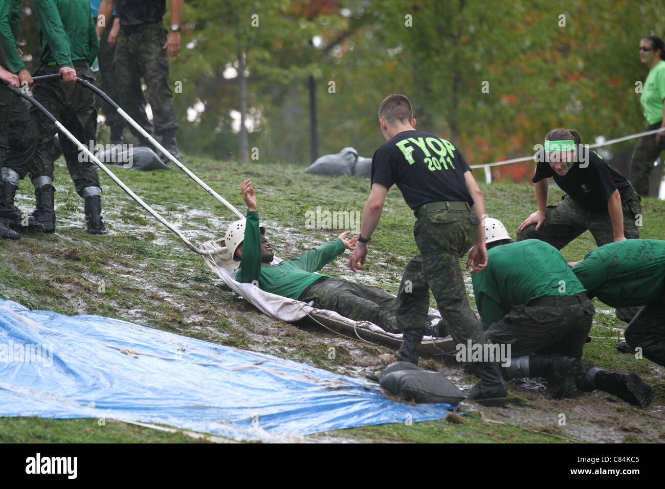 Man being pulled up a muddy hill on a emergency sled Stock Photo