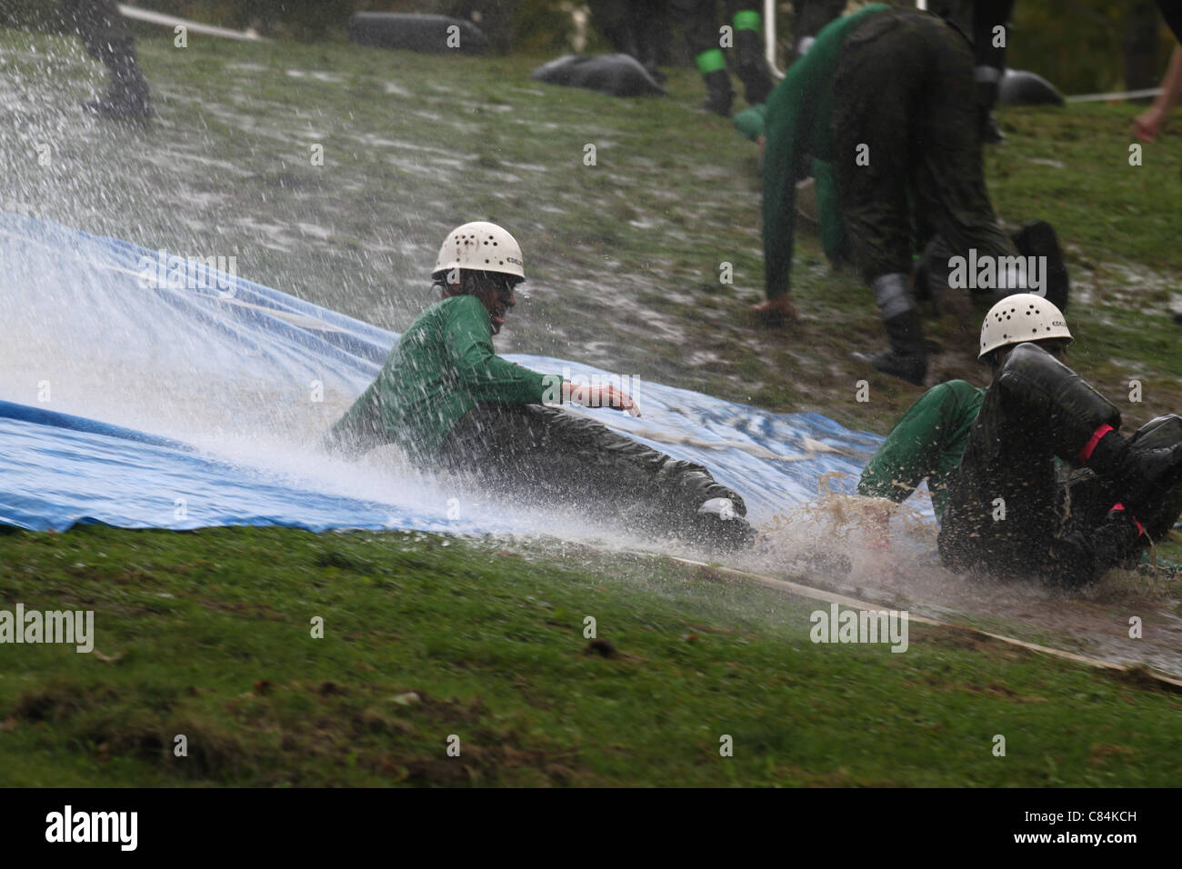 RMC first year recruits sliding down a muddy slope Stock Photo