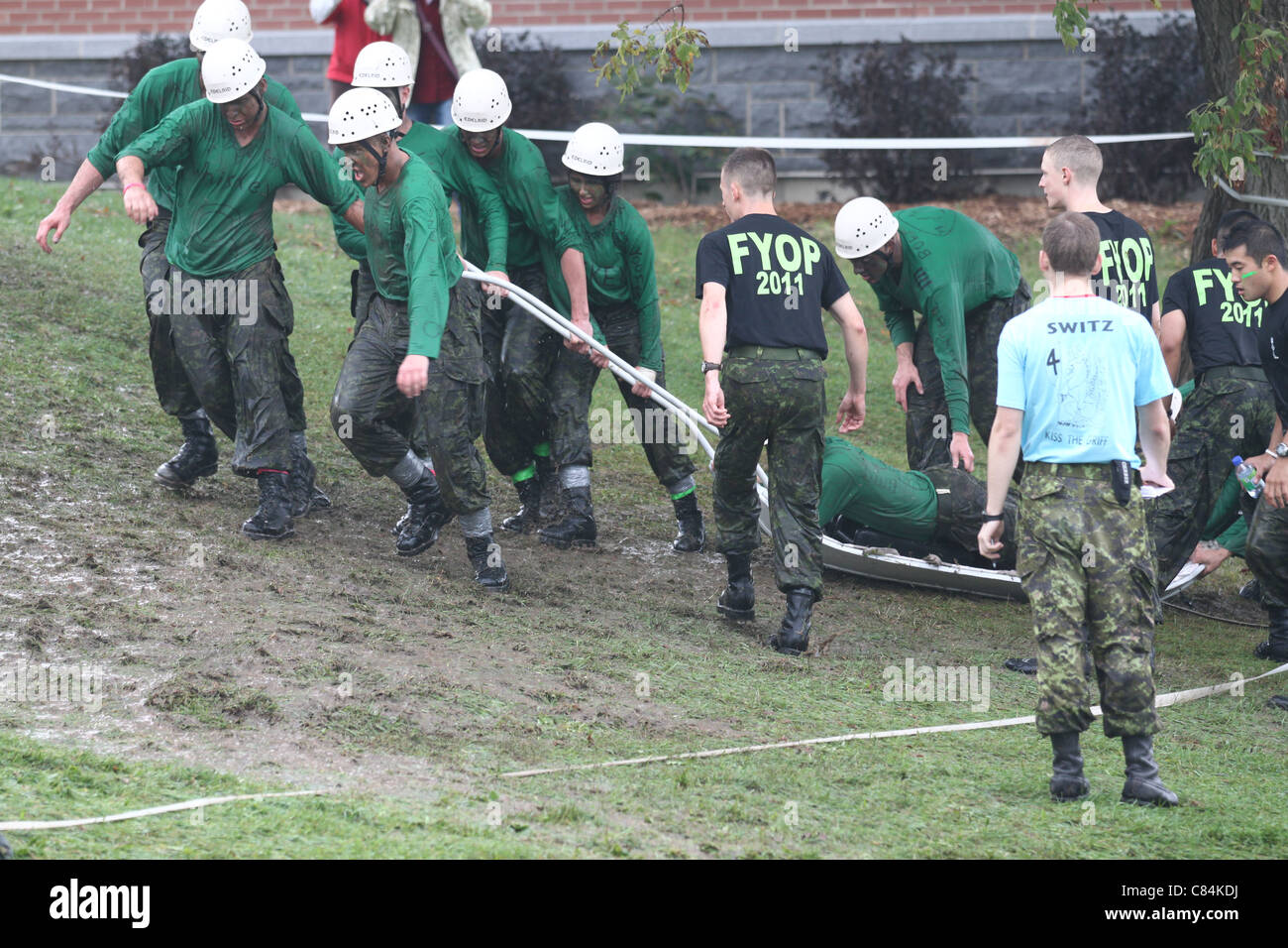 Green squadron pulling recruit up muddy hill Stock Photo