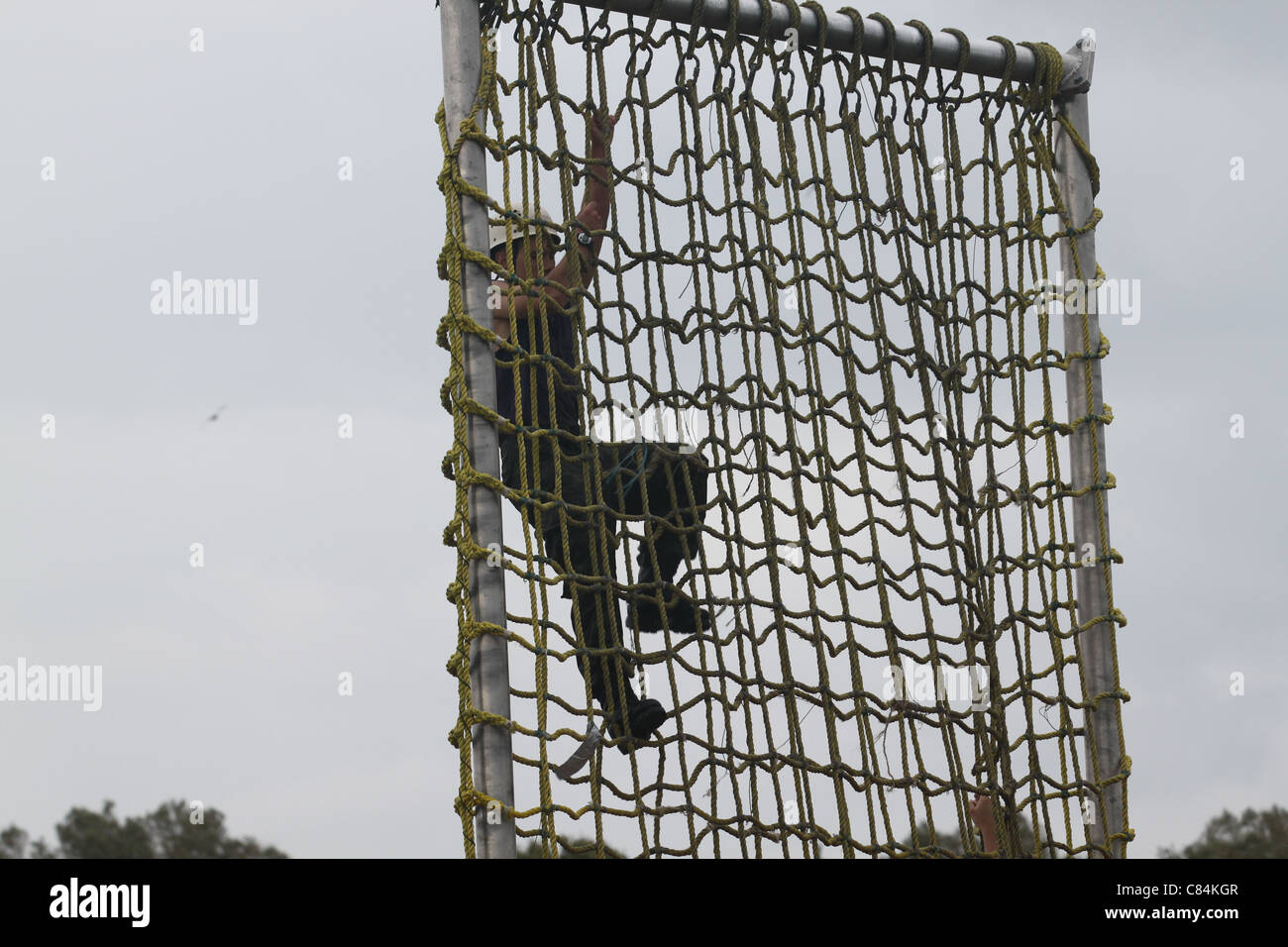 One male recruit climbing over a rope wall Stock Photo