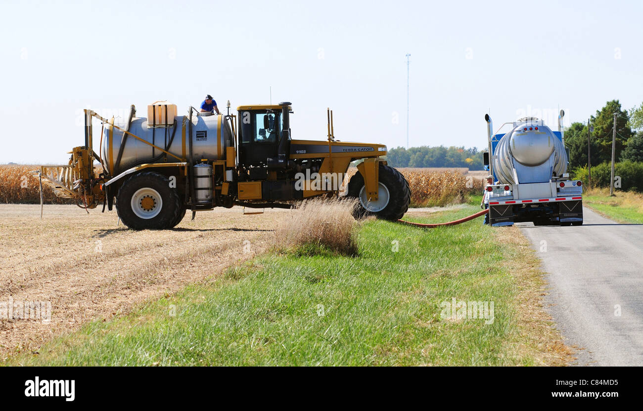 A Terra Gator crop sprayer is filled from a supply truck carrying liquid fertilizer Stock Photo