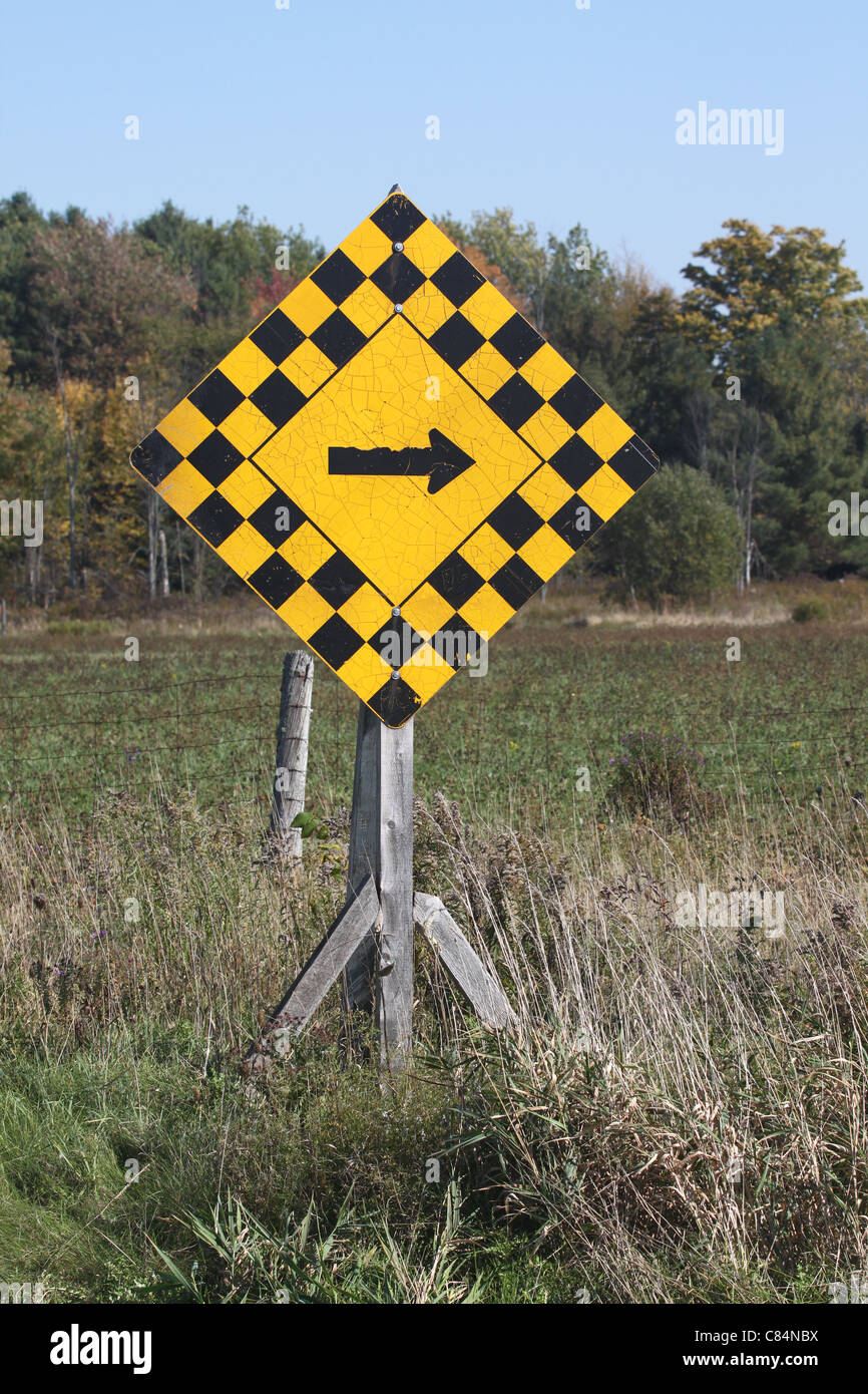 Yellow and black right-turn sign in rural setting Stock Photo