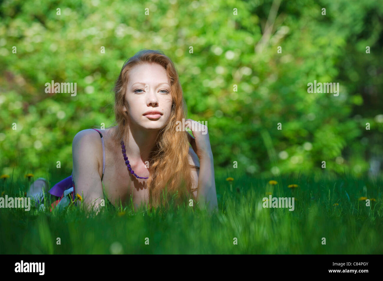 Portrait of red-haired girl on green grass relaxing Stock Photo