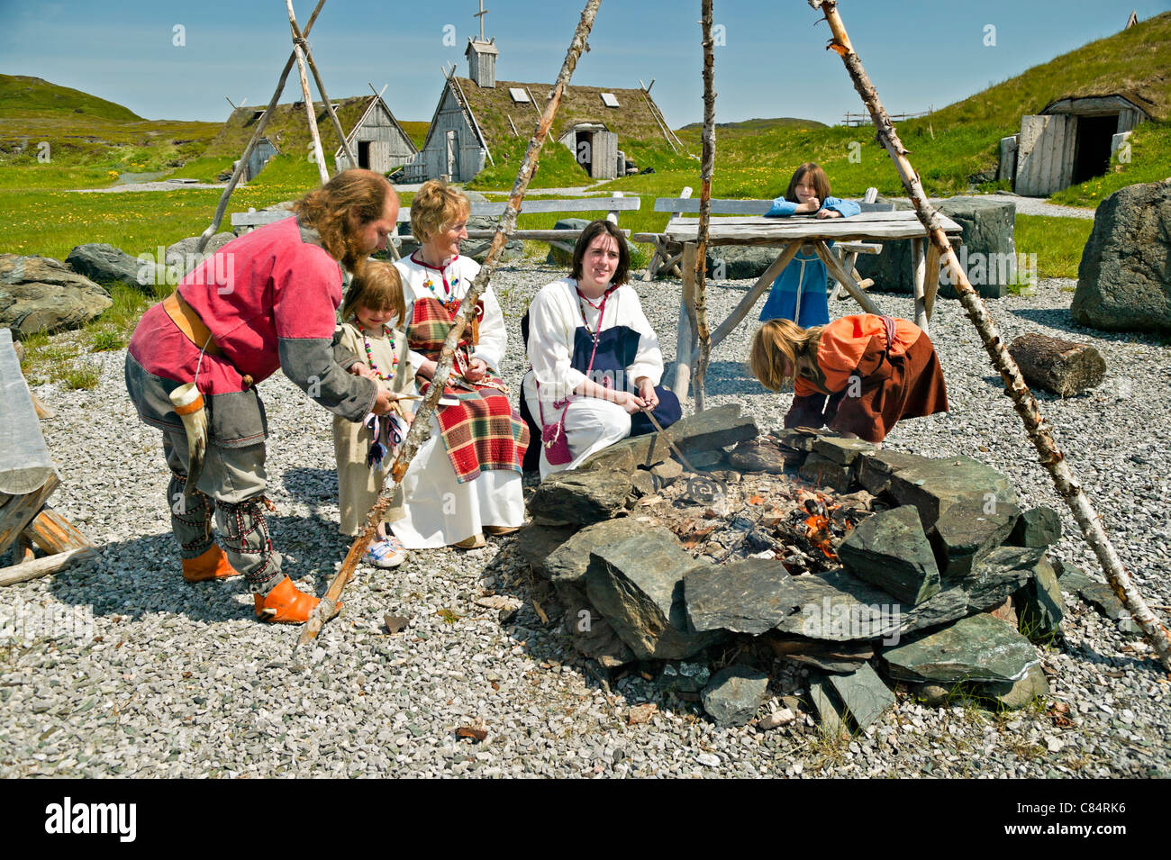 Viking Family Around An Open Fire Pit With Huts In The Background