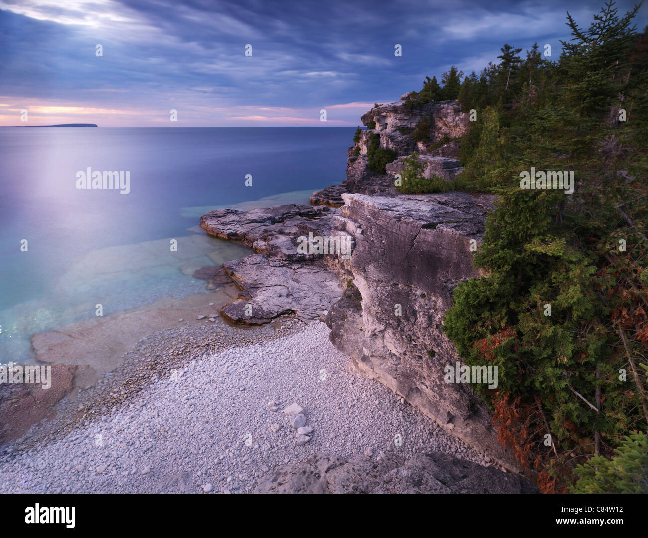 Beautiful sunset scenery of Georgian Bay rocky shore and cliffs inhabited by cedar trees. Bruce Peninsula National Park, Ontario Stock Photo