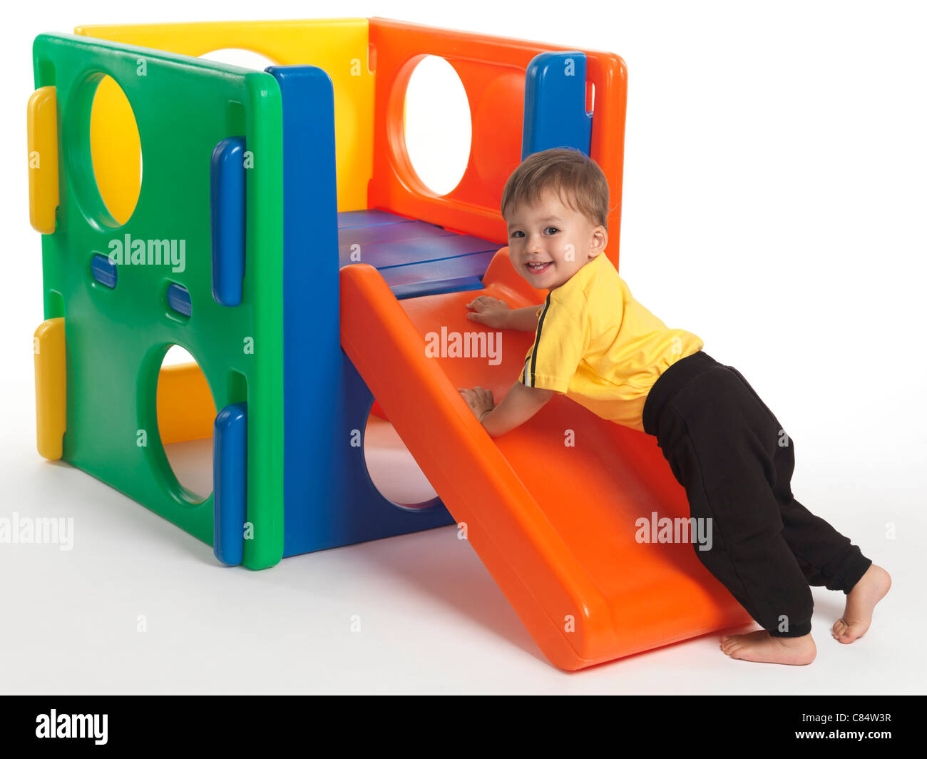 One and a half year old child climbing a slide. Isolated on white background. Stock Photo
