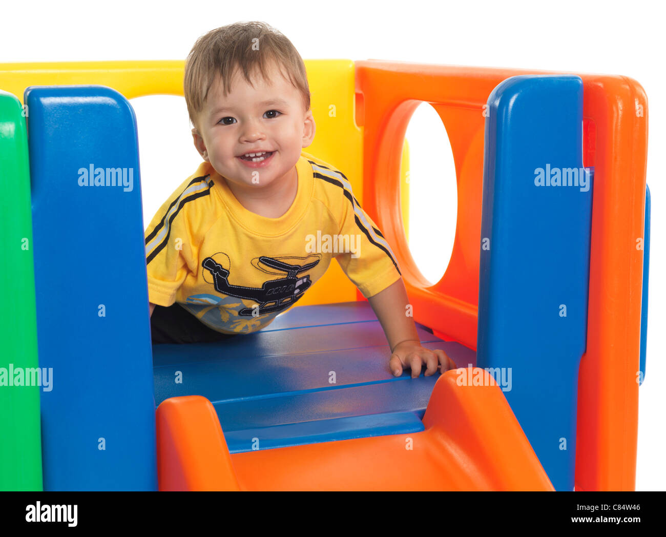 Happy one and a half year old child climbing a slide. Isolated on white background. Stock Photo