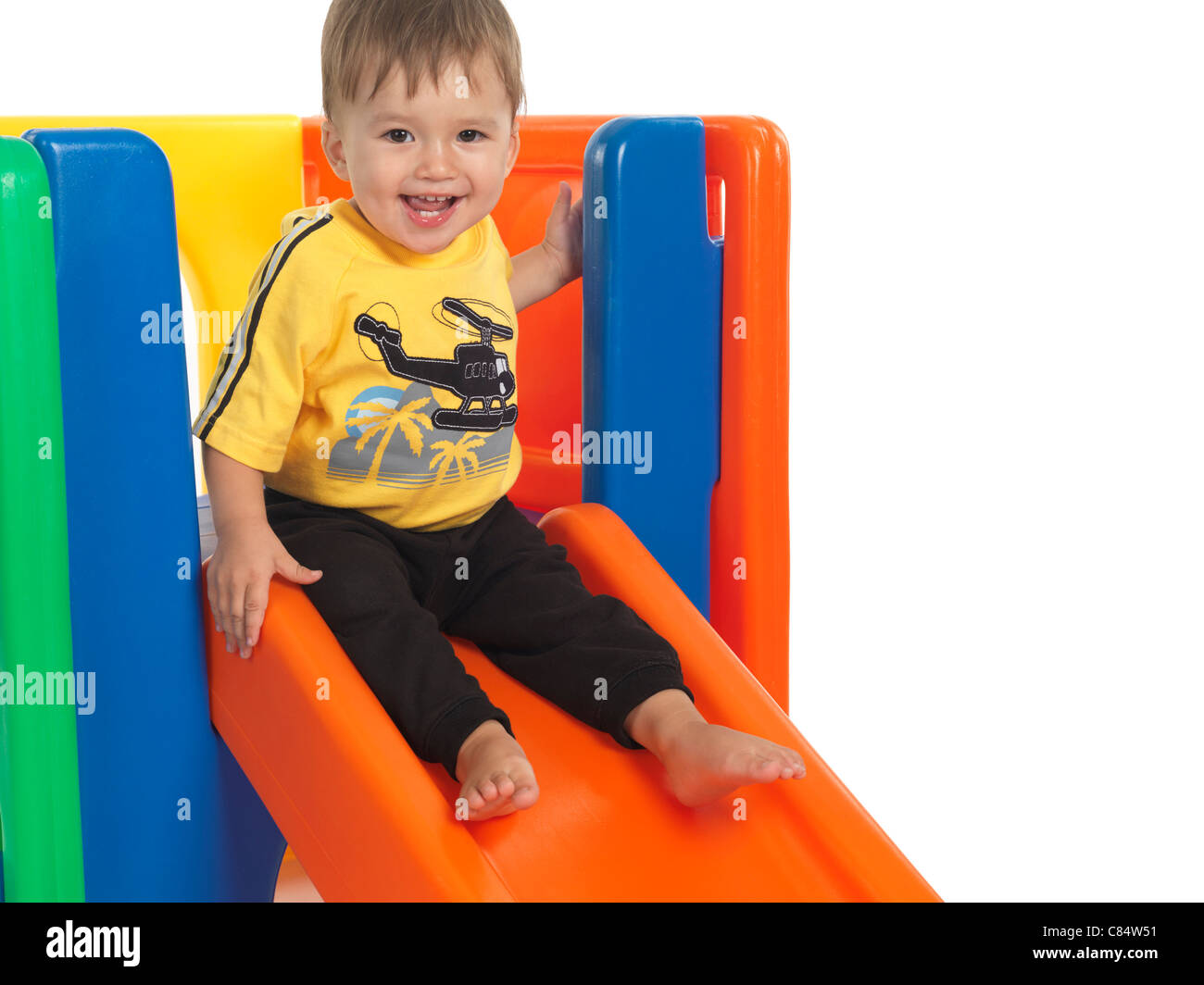 Happy one and a half year old child on a slide. Isolated on white background. Stock Photo