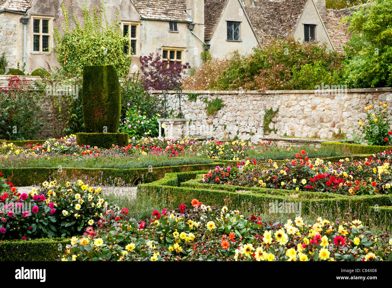 Formal garden of dahlias and low box hedges in front of a typical English country manor. Stock Photo