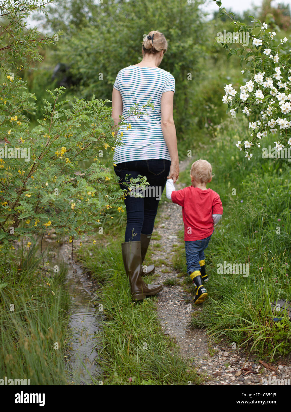 Mother and son walking on dirt path Stock Photo