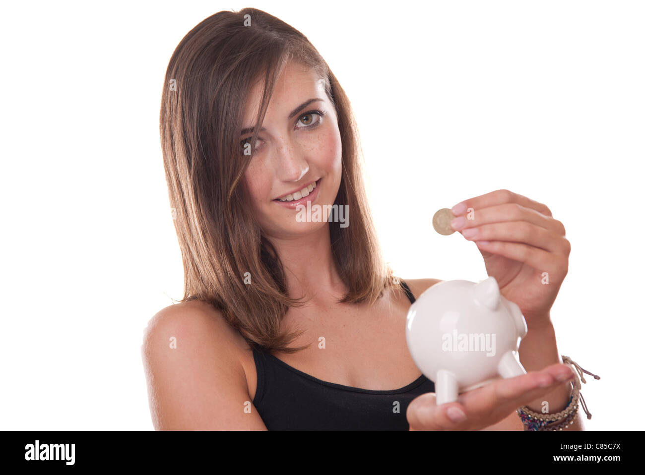 young woman putting a one pound coin into her piggy bank Stock Photo ...