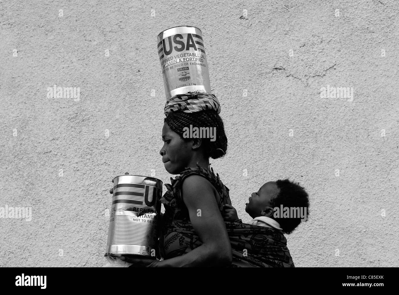 An internally displaced woman carrying cans of refined vegetable oil donated by USAID at World Food Programme WFP distribution point in North Kivu province, DR Congo Africa Stock Photo