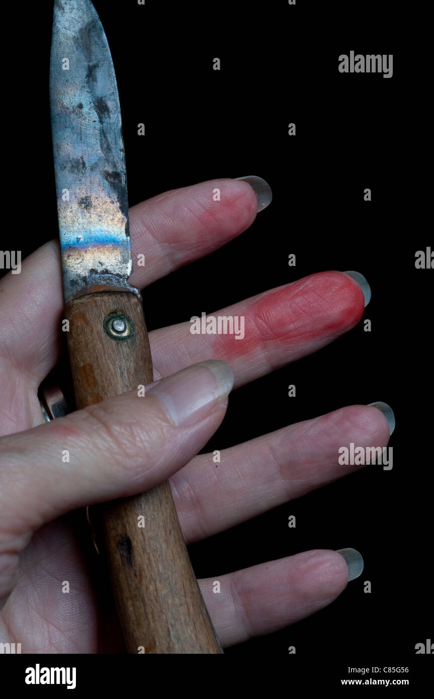 Penknife in female hand smudged with blood Stock Photo