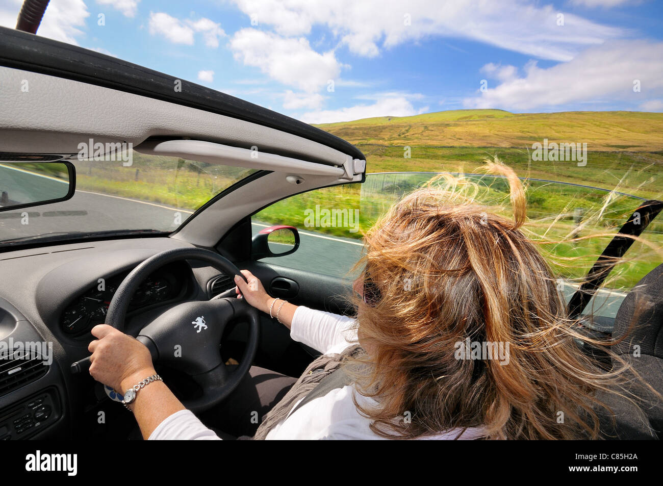 Open top sports car driven by female on open country road Stock Photo