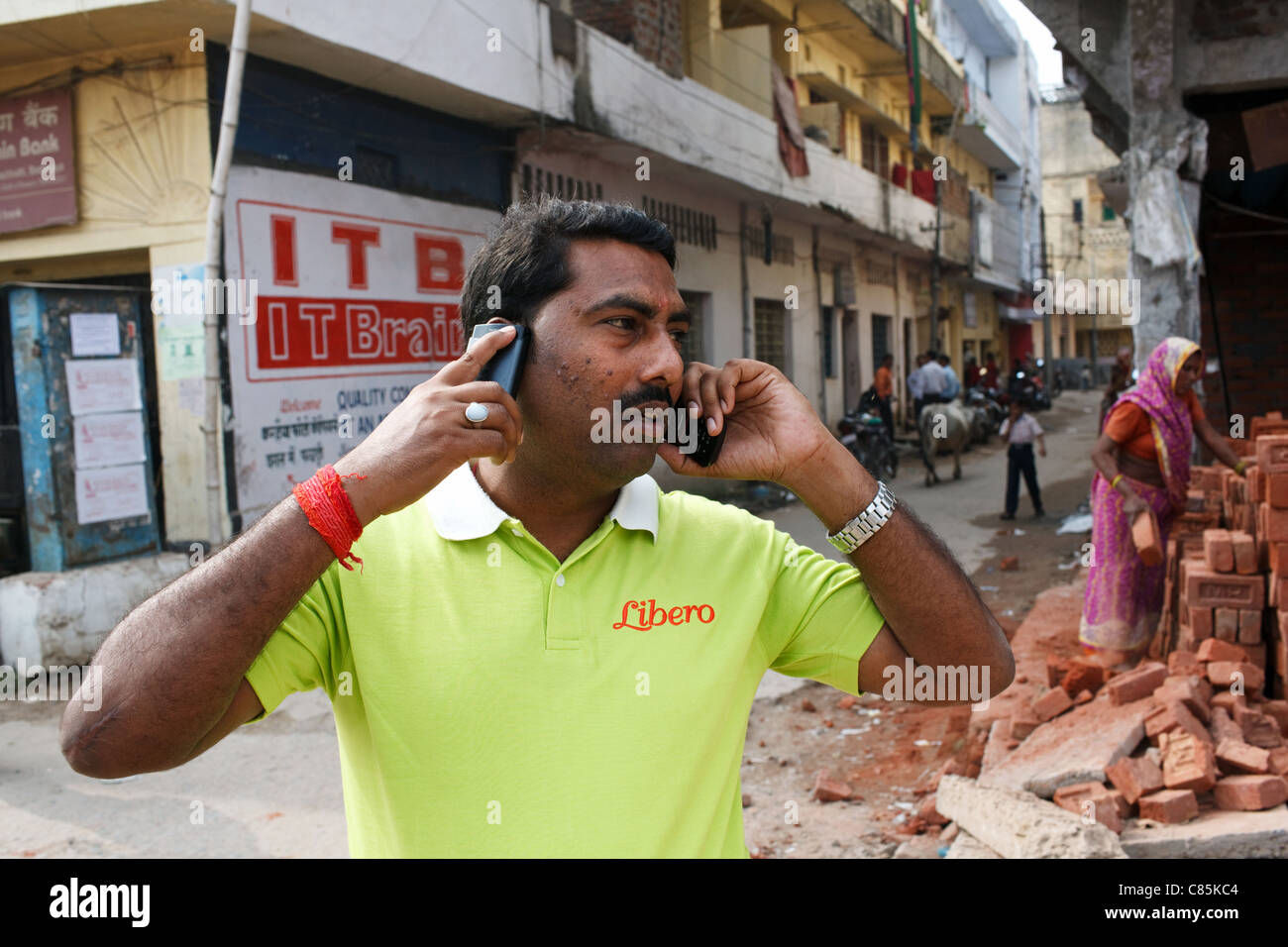 A man speaks on two mobile phones on the street in Patna, Bihar state, India. Stock Photo