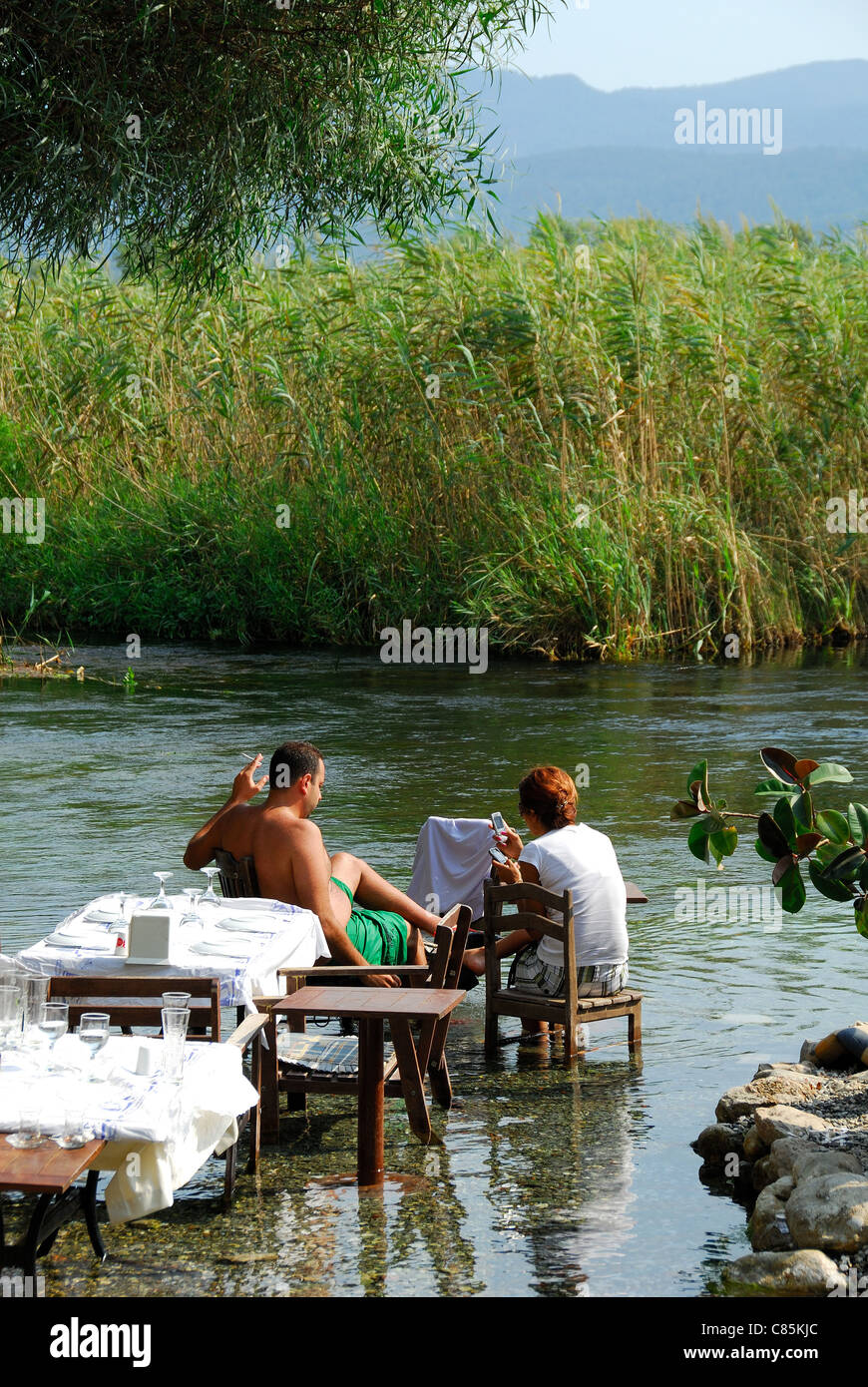 AKYAKA, TURKEY. A couple sitting at a restaurant by (or rather, in) the Azmak river. 2011. Stock Photo