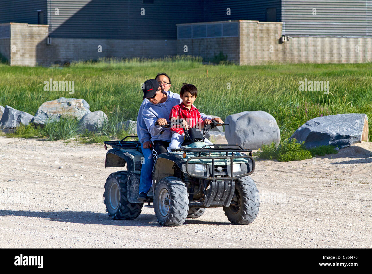 Native family (mother, father and young boy) rides a four wheel ATV around Churchill, Manitoba. Stock Photo