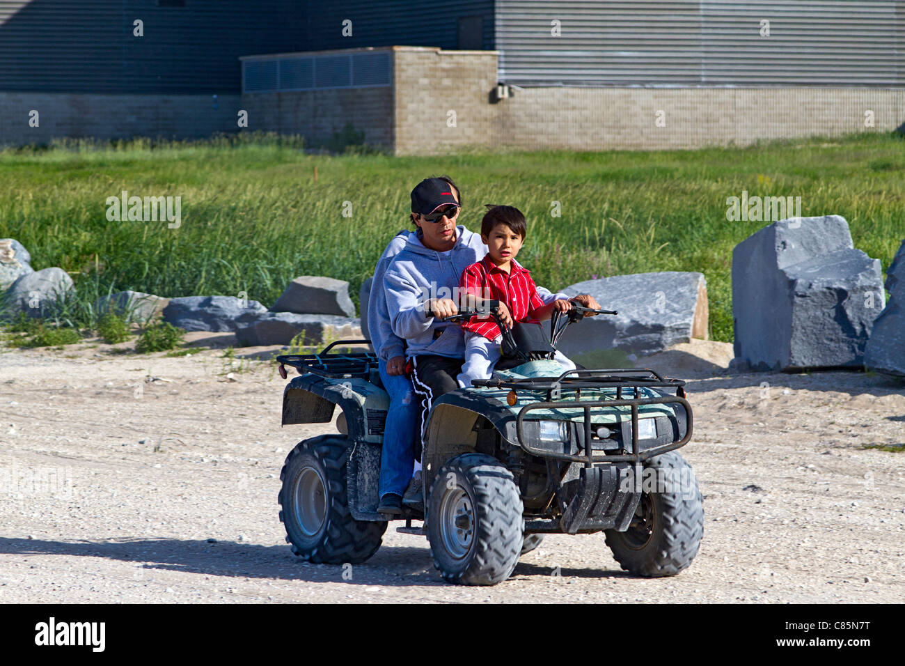 Native family (mother, father and young boy) rides a four wheel ATV around Churchill, Manitoba. Stock Photo