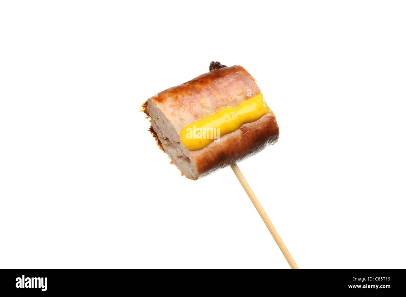 Piece of sausage with mustard on a cocktail stick isolated against white Stock Photo