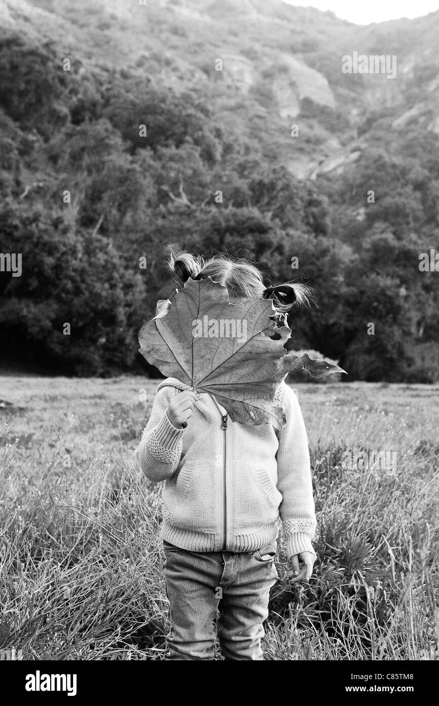Little girl covering her face with a leaf Stock Photo - Alamy