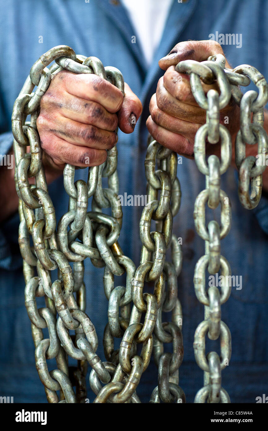 Caucasian worker holding chains Stock Photo