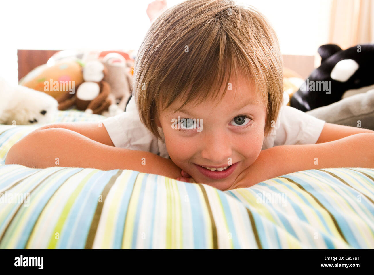 Boy laying on bed with striped sheets Stock Photo Alamy