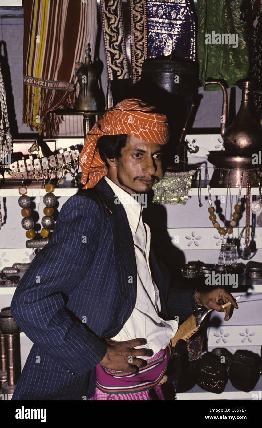 Portrait of a young adult Yemeni man chewing qat and smoking a cigarette in a jewelry store, Sana'a, Yemen Stock Photo