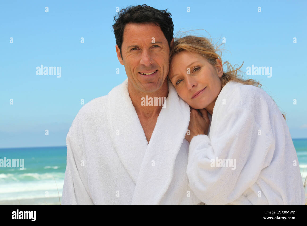 Attractive couple in bathrobes on the beach Stock Photo Alamy
