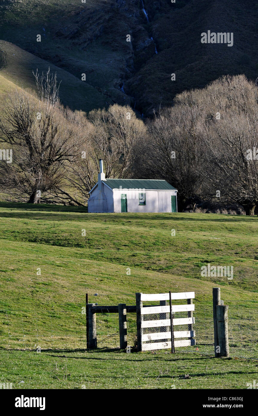 Trampers hut in pastoral setting at the base of a mountain range along the Mt Aspiring Road. Stock Photo