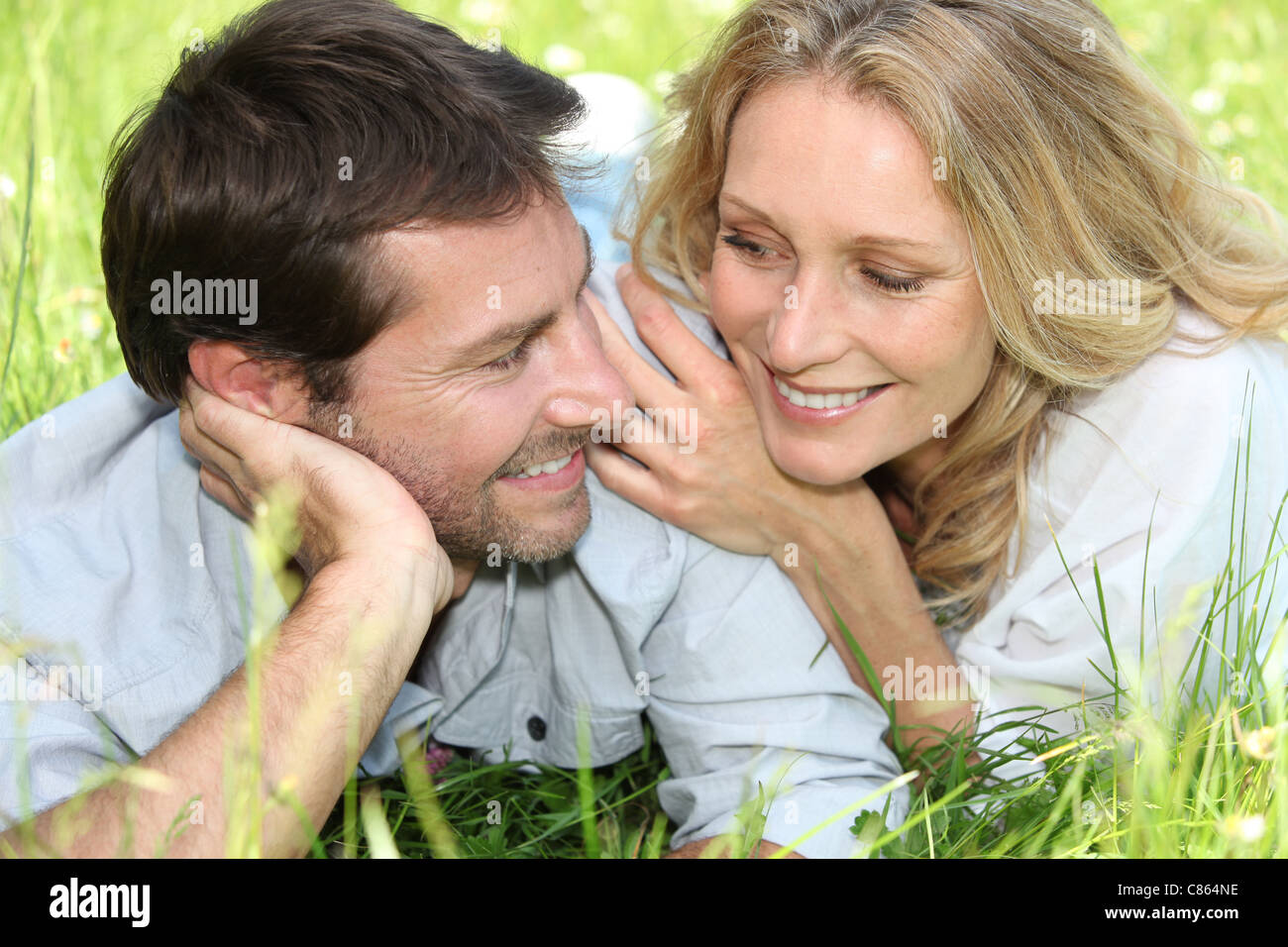 Happy couple lying on grass Stock Photo - Alamy