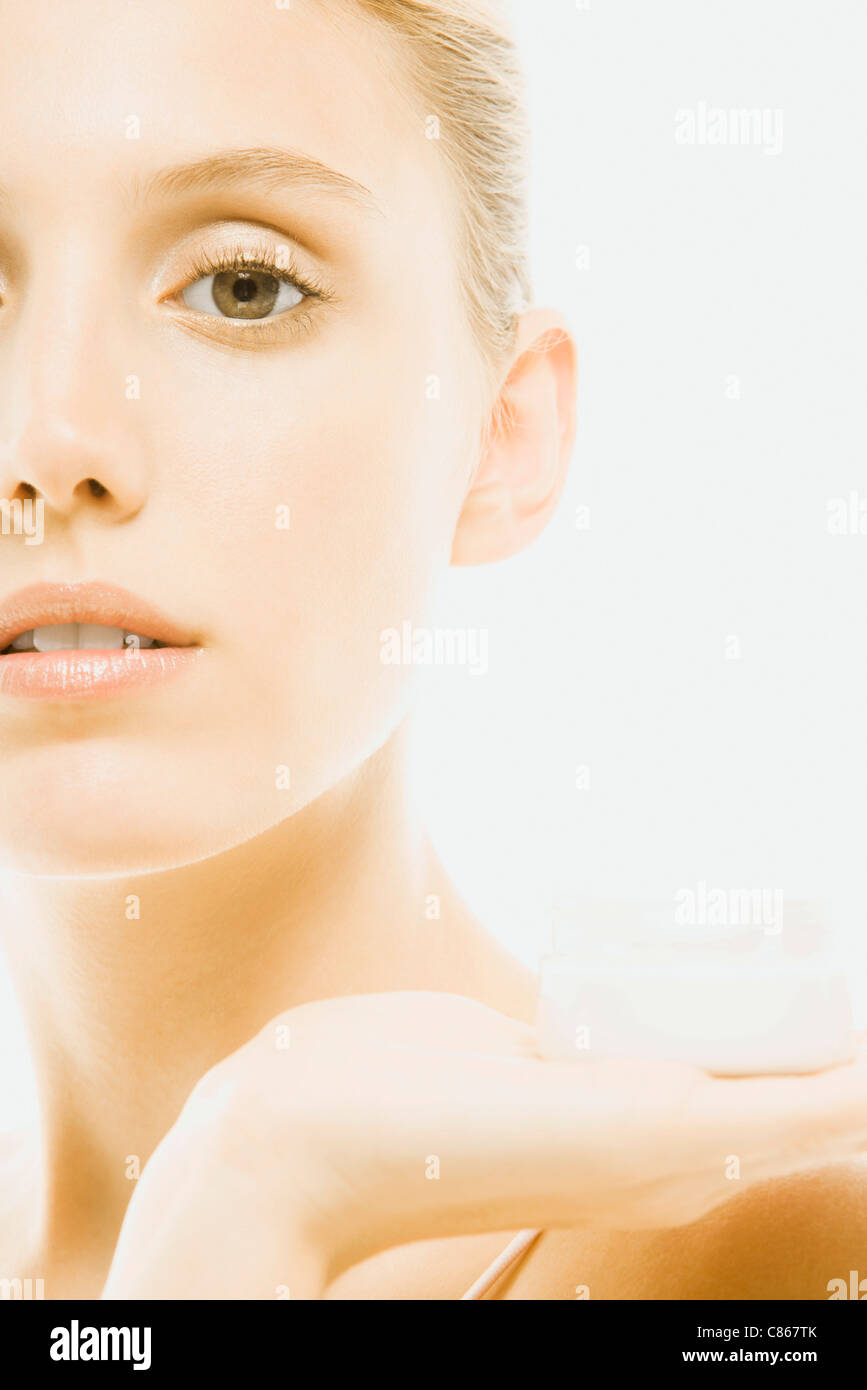 Young woman holding jar of moisturizer, cropped Stock Photo