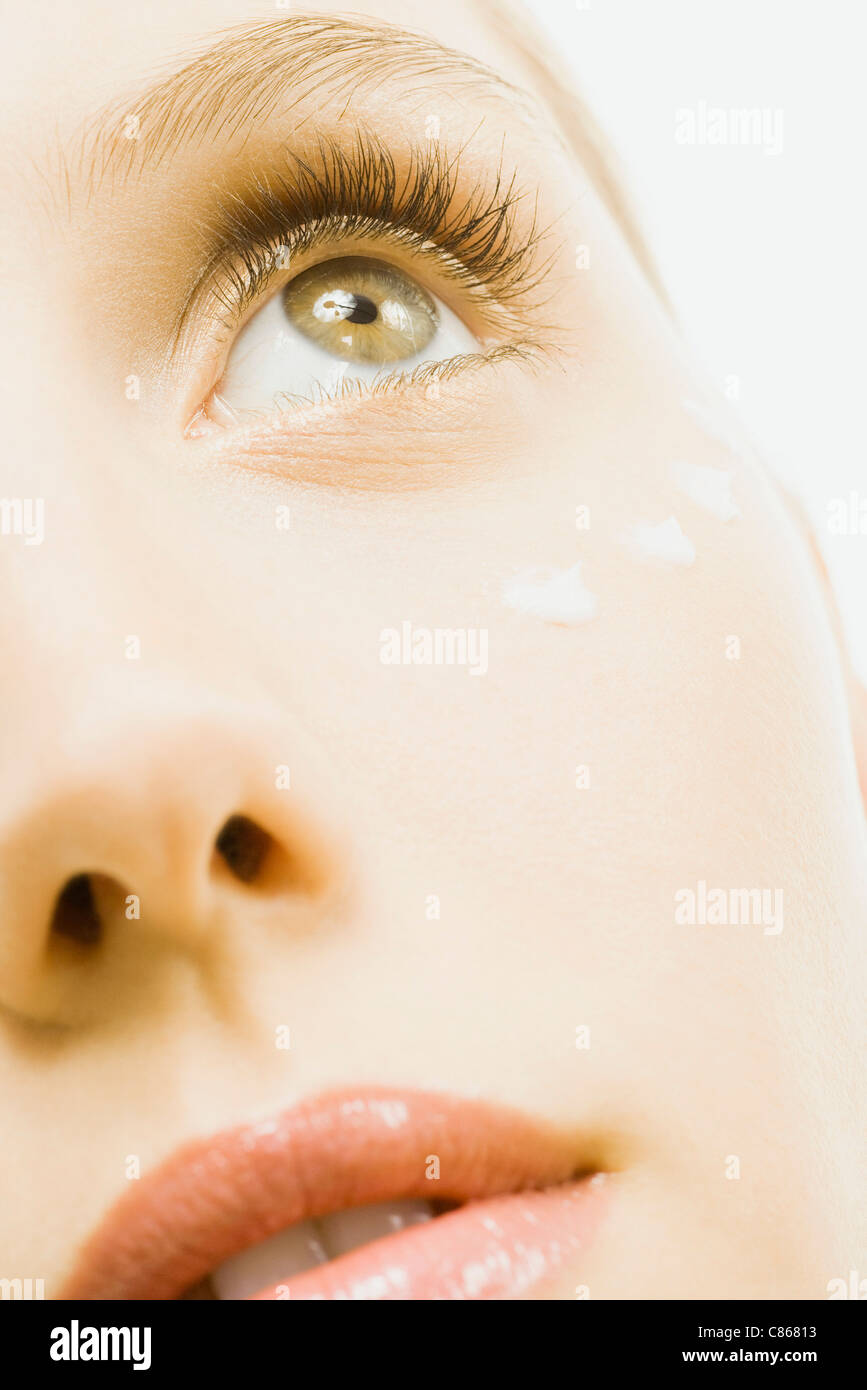 Woman with dots of undereye cream applied beneath eye, extreme close-up, cropped Stock Photo