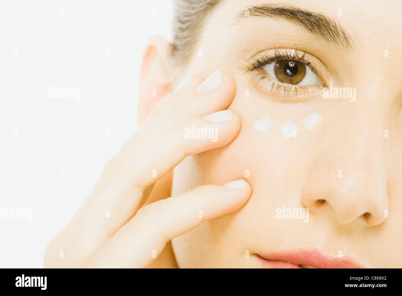 Woman applying undereye cream, close-up, cropped Stock Photo