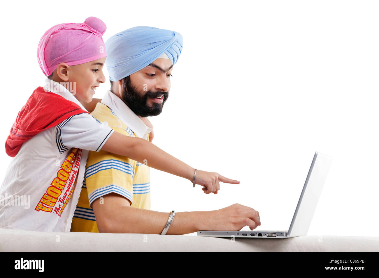 Sikh boy pointing at his fathers laptop Stock Photo