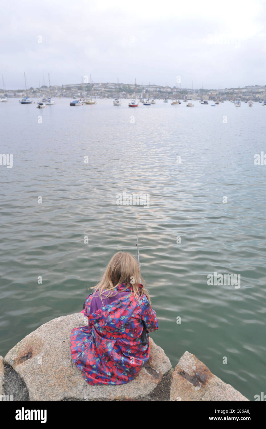 An 8 year old girl fishing in Flushing, Cornwall with Falmouth in the background Stock Photo