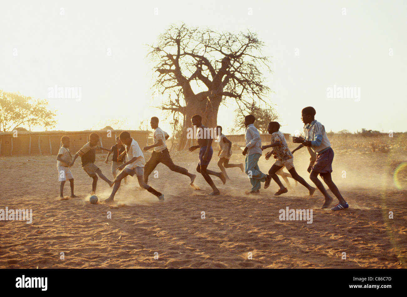 Dodoma, Tanzania. Teenagers playing football in the dust of the late afternoon sun. Stock Photo