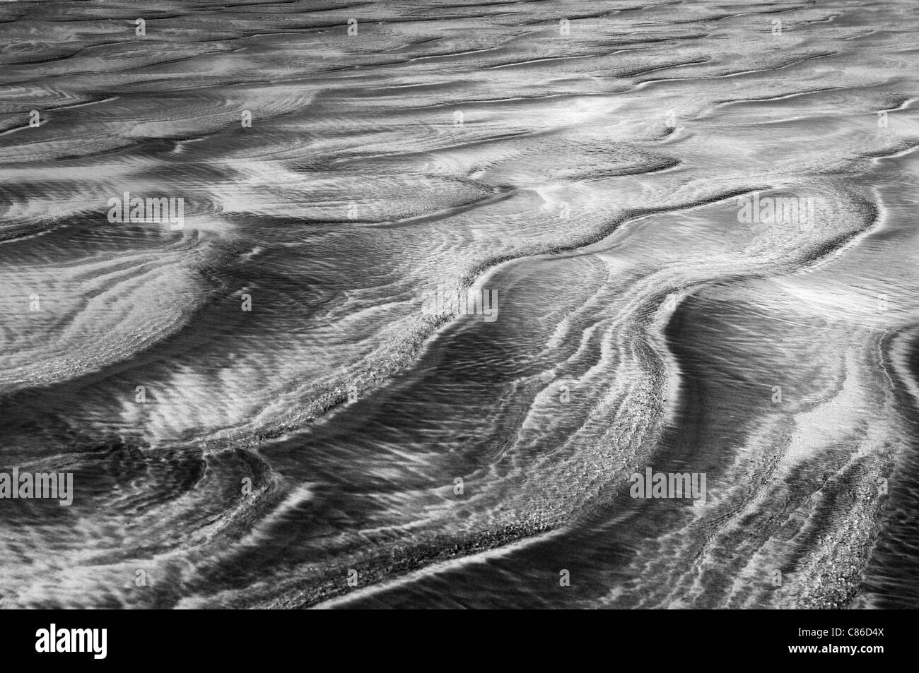 Patterns in the sand left by the retreating sea. Stock Photo