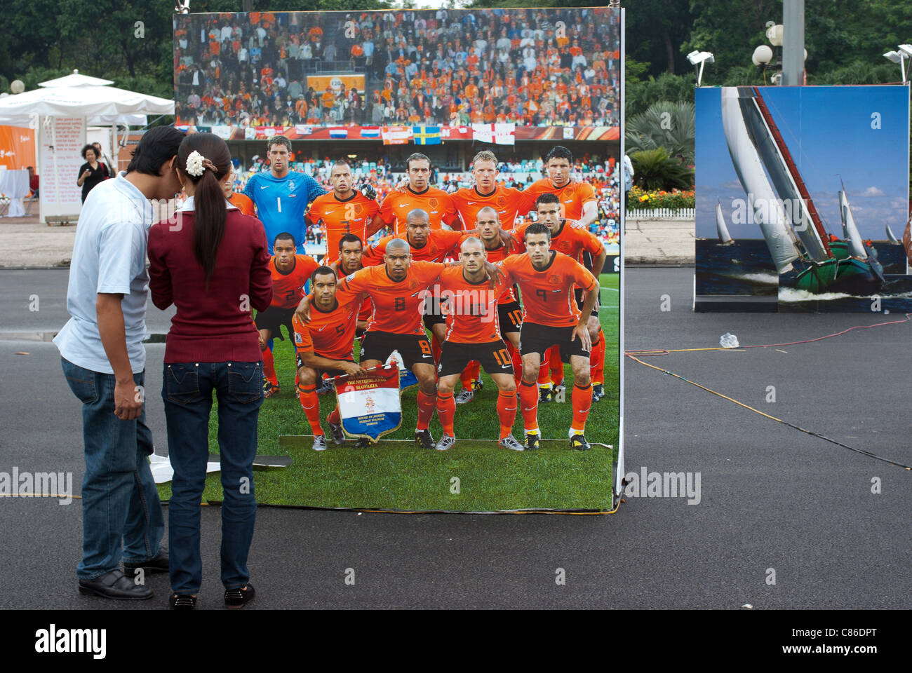Young Vietnamese couple starring at the Holland national soccer team poster at an exposition in Saigon, Vietnam Stock Photo
